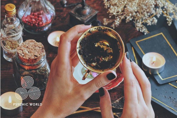 woman holding a cup of tea doing a tea leaf reading