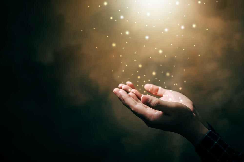 Praying hands against a dark blessing background.