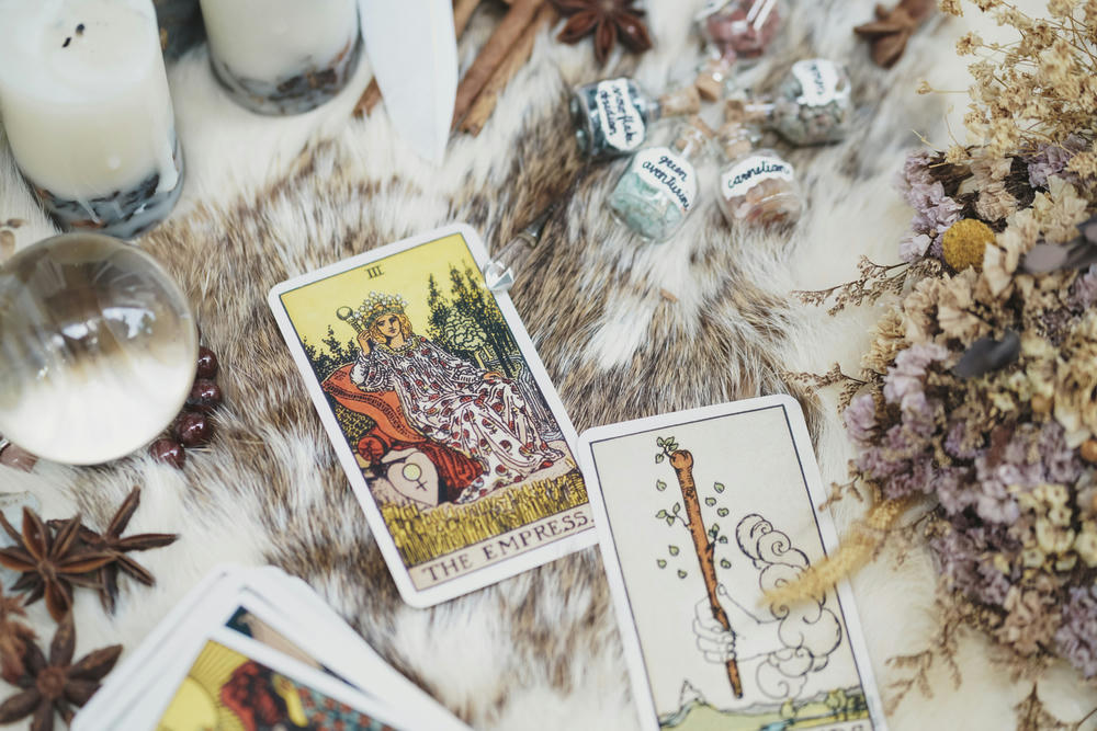 Fortune teller concept with a crystal ball, healing stones, incensed candles and cards scattered.