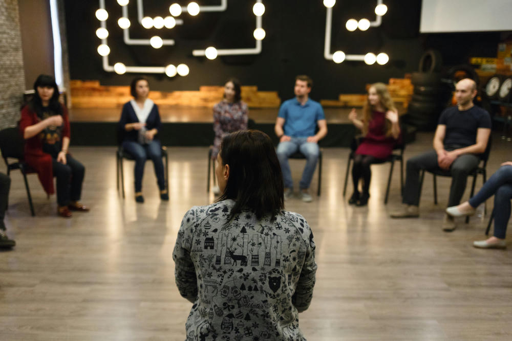 A teacher sits back in front of a group of students.