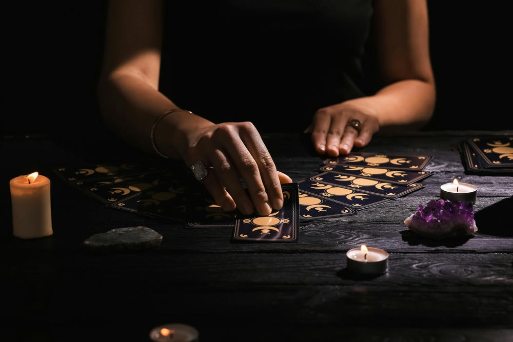 Soothsayer predicting the future with tarot cards at a table in the darkness.